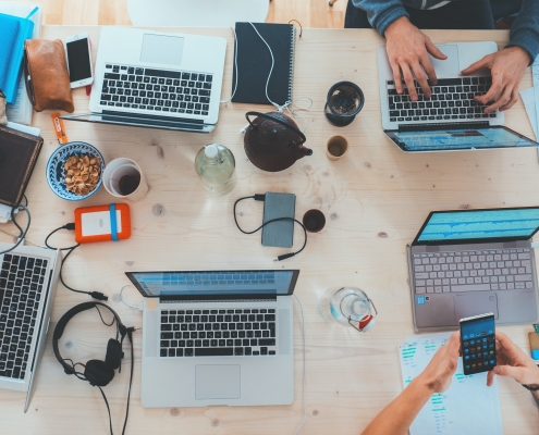 marvin-meyer-SYTO3xs06fU-unsplash view from above of meeting table with laptops and arms visible; soft skills