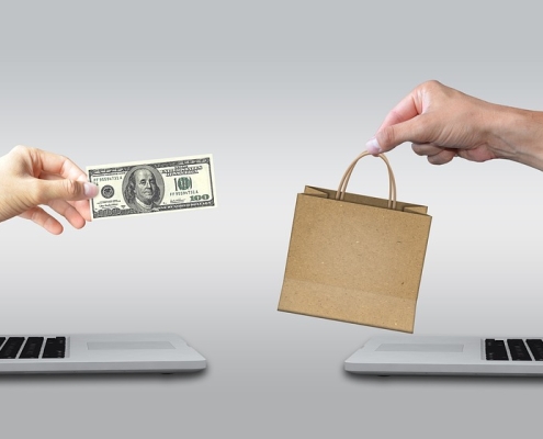 ecommerce-2140604_1280 Hands reaching toward each other from laptops. One holding money, the other holding a bag. purchasing carbon credits