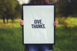 simon-maage-KTzZVDjUsXw-unsplash give thanks on white sign held in front of a person; sharing gratitude