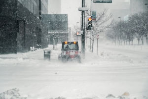 city scene with heavy snowfall and a street-cleaning truck blurred from snowfall