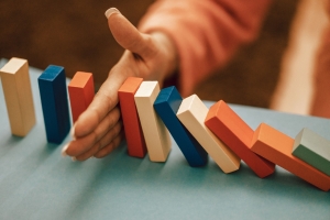 balance-6815204_1280 line of colored dominos falling with a hand stopping the fall; hedging - identifying risks