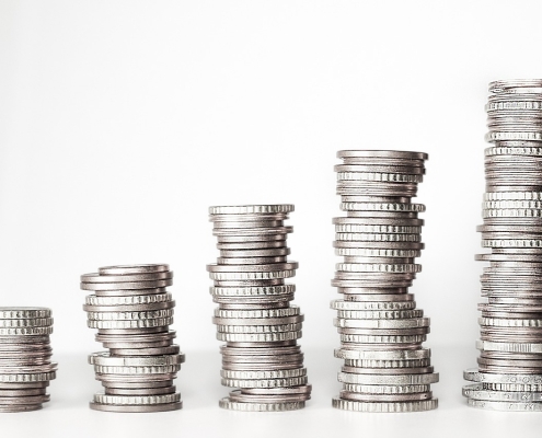 money-2180330_1280 stacks of silver coins on white background set up like a graph; key energy indicators