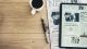 coffee cup, pen, newspaper and phone with the words "news" on it on a wood table; current events