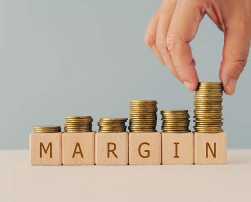 margin text on wooden cube blocks with hand arranged stack of coins including copy space blocks with the letters - margin - on them and stacks of coins of increasing levels on top of the blocks; Hedging 301 - Financial Options - how we use them