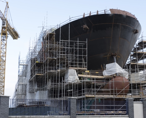 Shipbuilding progress scaffolding and crane large nautical vessel being built at dock port harbour harbour Glasgow large ship surrounded by scaffolding; US targets Chinese ships