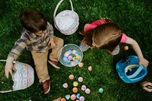 overhead view of boy and girl sitting on the grass with baskets and colorful Easter eggs; hope at Easter