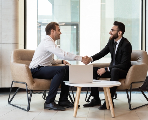Horizontal image european and arabian businesspeople accomplish meeting shaking hands two men sitting and shaking hands in a business setting; meet the team - allan degenhardt