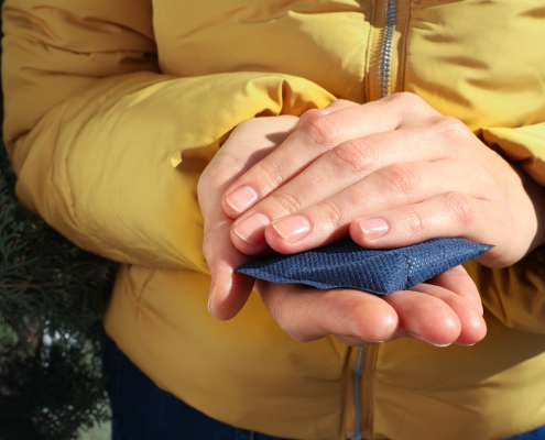 Woman holding hand warmer outdoors, closeup view