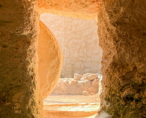view from inside a rock structure or tomb out the entrance with a partial view of a rock outside the entrance that has been pushed to the side; hope at Easter