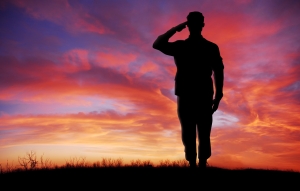 Soldier full body silhouette saluting gesture at sunset copy space silhouette of a soldier saluting against a colorful sunset; Memorial Day Remembering