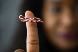 African American Woman With Memory Ribbon. Don't forget image of blurry woman's face in background with index finger in foreground with string tied around it, Memorial Day Remembering