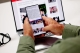 image of hands holding a phone with text and images on the screen in front of a laptop screen with text and images on it; Current events May 2025 - global supply shifts
