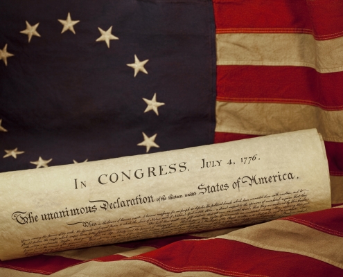 USA Declaration of Independence Lying on Grungy Betsy Ross Flag image of rolled up Declaration of Independence resting on early American flag; Fourth of July, freedom