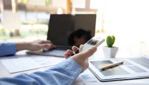 hand holding smart phone, resting on a desk with an open laptop and other desk accessories; Current Events August 2025; Q&A with the Westlark Team