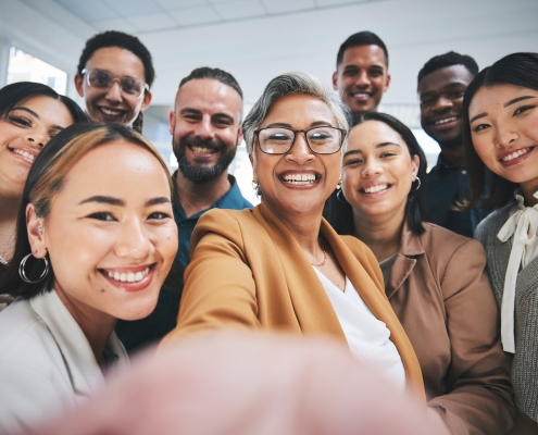Work selfie, portrait and happy business people together for bonding, team building or group. Smile, diversity and a mature manager taking a photo with friends for social media, about us or faq group of employees, men and women, taking a "selfie"; Labor Day - the importance of hard work
