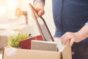 Attentive precise man packing his belongings person packing a box with personal possessions, layoff, firing; data integrity EIA