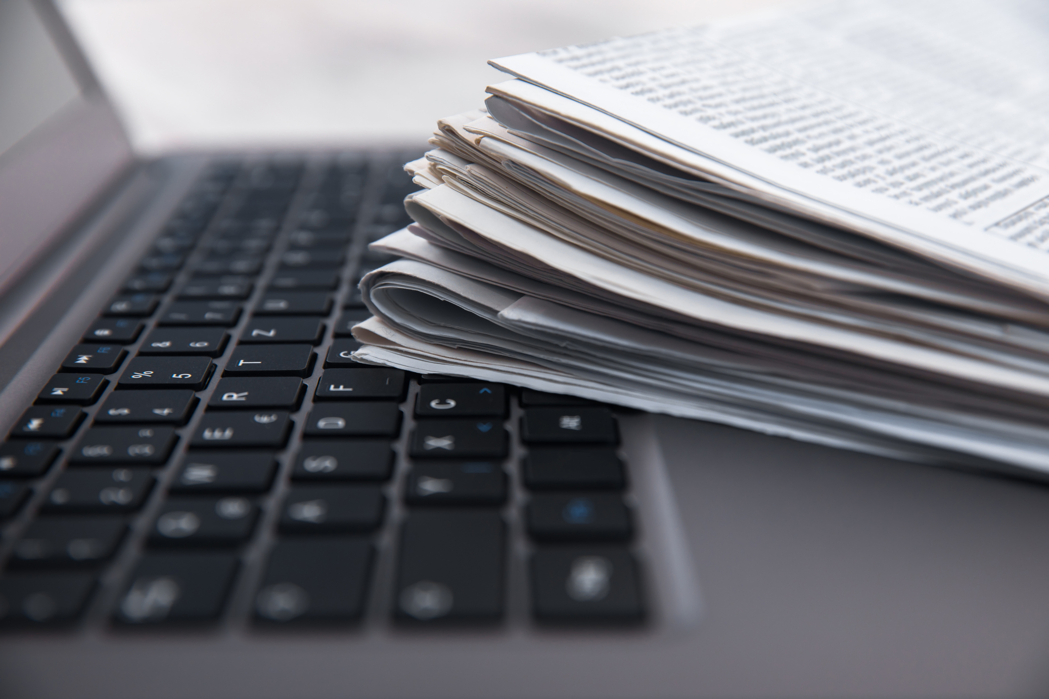 stack of newspapers on top of laptop keyboard; words matter