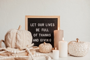 Felt letter board and text let our lives be full of thanks and giving. Autumn table decoration. Interior decor for thanksgiving and fall holidays with handmade pumpkins and candles letterboard saying: "Let our lives be full of thanks and giving." in front of fall decorations; giving thanks