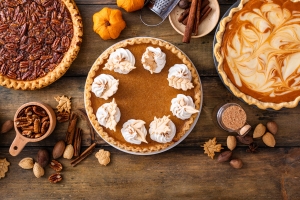 Variety of traditional Thanksgiving pies on light background three pies with pumkins and fall decor; giving thanks