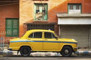 An Ambassador taxi is parked on the streets in Kolcata. The Ambassador taxi is no more built by Hindustan Motors but thousands still remain on the streets of India. Ambassador taxi parked outside a building in India; Ambassador was made by Hindustan; India Fuel Revolution autos