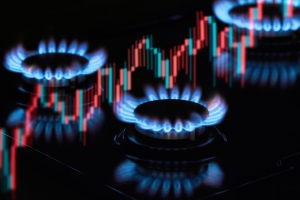 Flaming gas burners on household kitchen stove with an exchange graph of the growth in the cost of natural gas prices gas burners against a background of stock chart data; international market highlight; continued Middle East disruption; hedging financial spreads