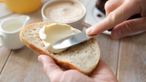 Spreading soft butter on white bread toast hands spreading butter on a piece of bread with image of butter in background; hedging financial spreads